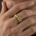 Load image into Gallery viewer, Gold plated floral band ring worn on a finger, lifestyle photo featuring warm tone finish and strong statement band presence.
