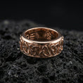 Load image into Gallery viewer, Rose gold plated Celtic triquetra band ring on textured volcanic rock, centered studio-style close-up showcasing soft rosy glow and crisp Celtic knot detailing with a refined finish.