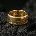 Load image into Gallery viewer, Gold plated Egyptian symbols band ring on textured volcanic rock, premium close-up with warm reflective shine across the Eye of Horus, ankh symbol, and raised engraved lines.