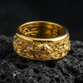 Load image into Gallery viewer, Gold plated oriental dragon band ring on textured volcanic rock, premium close-up with warm reflective shine across the dragon head, flowing cloud scrolls, and raised ornamental contours.