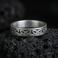 Load image into Gallery viewer, Oxidized Celtic knot band ring on volcanic stone, macro close-up showing darkened recessed background and raised interlaced pattern.
