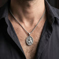 Load image into Gallery viewer, Oxidized Saint Jude pendant with haloed saint figure worn on the neck in a lifestyle jewelry shot, styled against the chest for a devotional and timeless look