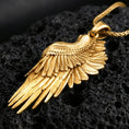 Load image into Gallery viewer, Gold plated angel wing pendant with detailed feather layers, elegant tapered shape, and symbolic celestial styling showcased on black volcanic rock in a refined macro jewelry image