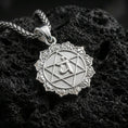 Load image into Gallery viewer, Polished silver heart chakra necklace with raised Anahata symbol, geometric star design, and detailed circular frame placed on textured volcanic rock in a premium studio product shot