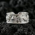 Load image into Gallery viewer, Polished silver mythic faces cuff band ring on volcanic stone, crisp product photo emphasizing clean shine and high-definition sculpted faces.