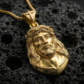 Load image into Gallery viewer, Gold plated Jesus Christ necklace with detailed sacred face, crown of thorns, and bust-style medallion design showcased on black volcanic rock in a refined macro jewelry image