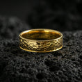 Load image into Gallery viewer, Gold plated hammered texture band ring on volcanic stone, premium close-up emphasizing warm gold tone across the faceted surface and refined shine.