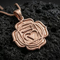 Load image into Gallery viewer, Rose gold plated spiritual chakra pendant with heart chakra symbol, faceted sacred lines, and floral lotus border resting on volcanic rock in an elegant close-up product presentation