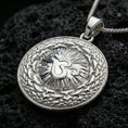 Load image into Gallery viewer, Polished silver spiritual necklace with raised Om symbol, round medallion form, and intricate mandala relief placed on textured volcanic rock in a premium studio product shot