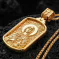Load image into Gallery viewer, Gold plated Saint Anastasia pendant with orthodox saint portrait, cross symbol, and framed devotional silhouette showcased on black volcanic rock in a refined macro jewelry image