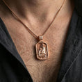 Load image into Gallery viewer, Rose gold plated religious Jesus pendant with seated sacred portrait and framed design worn on the neck in a refined lifestyle shot with a warm and elegant presentation