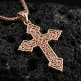 Load image into Gallery viewer, Rose gold plated religious cross pendant with intricate Celtic linework, open center ornament, and elegant pointed silhouette resting on volcanic rock in an elegant close-up product presentation