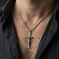 Load image into Gallery viewer, Oxidized sterling silver crucifix pendant worn on the neck, lifestyle image focusing on bold contrast, visible relief, and everyday faith styling.