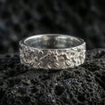 Load image into Gallery viewer, Polished silver floral engraved band ring on volcanic stone, macro shot emphasizing crisp flower relief, smooth shine, and clean botanical detailing.