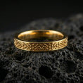 Load image into Gallery viewer, Gold plated Celtic knot band ring on volcanic stone, premium macro close-up showcasing warm gold tone across the continuous interlace design.