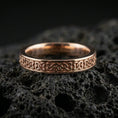 Load image into Gallery viewer, Rose gold plated Celtic knot band ring on volcanic stone, elegant macro photo capturing soft rose reflections and the refined braided motif.