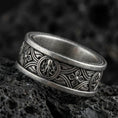 Load image into Gallery viewer, Oxidized sterling silver spinner ring on volcanic stone, macro close-up highlighting the Celtic knotwork band, raised medallion details, and antique shadow contrast.
