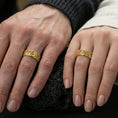 Load image into Gallery viewer, Gold plated quatrefoil cross band ring worn on the finger, lifestyle shot featuring rich golden glow and prominent cross symbols for statement wear.