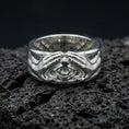 Load image into Gallery viewer, Polished silver protective eye ring on volcanic stone, crisp macro shot emphasizing smooth reflective edges, clean hand contours, and defined iris detail.