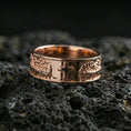 Load image into Gallery viewer, Rose gold plated cross band ring on volcanic stone, refined macro close-up showcasing soft rose warmth, sculpted cross focal point, and high-relief accents.
