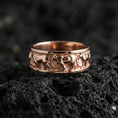 Load image into Gallery viewer, Rose gold plated horse band ring on volcanic stone, refined macro close-up showcasing soft rose warmth and the continuous horse-pattern band texture.