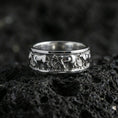 Load image into Gallery viewer, Polished silver horse band ring on volcanic stone, crisp macro shot emphasizing bright reflective edges and the detailed horse silhouettes in clean relief.