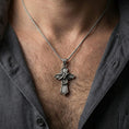 Load image into Gallery viewer, Oxidized snake cross pendant with wrapped serpent detail worn on the neck in a lifestyle jewelry shot, styled against the chest for a bold and symbolic statement look