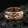 Load image into Gallery viewer, Mechanic style spinning fidget band ring on black volcanic stone, shown in a rose gold plated finish with a softer warm tone that enhances the sculpted faceted pattern.