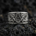 Load image into Gallery viewer, Sterling silver Masonic square and compass band ring on black volcanic stone, photographed with an oxidized patina that darkens the recessed background and sharpens the raised emblem details.