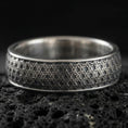 Load image into Gallery viewer, Oxidized sterling silver geometric band ring on dark volcanic rock, repeating interlocking maze texture, premium macro product shot.