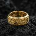 Load image into Gallery viewer, Gold plated spinning wave band ring on volcanic rock, detailed nautical swirl engraving on rotating center, luxury jewelry product photography.