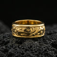 Load image into Gallery viewer, Gold plated spinning cloud motif band ring on volcanic rock, detailed swirl and floral relief on rotating band, luxury jewelry product photography.