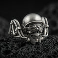 Load image into Gallery viewer, Oxidized sterling silver biker skull ring on dark volcanic rock, helmet and goggles relief with detailed beard, premium macro product shot.