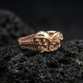 Load image into Gallery viewer, Rose gold plated sterling silver gothic biker skull ring on volcanic stone, sculpted helmeted skull relief with wing detail and deep contrast, minimal high-end close-up.