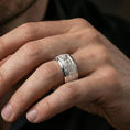 Load image into Gallery viewer, Polished silver engraved ornament band ring on finger, crisp floral panel and detailed filigree borders, refined everyday wear close-up.