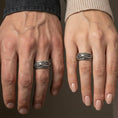 Load image into Gallery viewer, Oxidized sterling silver koi fish spinner band worn on finger, koi and wave engraving detail on rotating center, natural lifestyle hand shot with shallow depth of field.