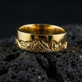 Load image into Gallery viewer, Gold plated Grand Teton mountain band ring on volcanic rock, detailed peak landscape engraving with rugged texture, luxury jewelry product photography.