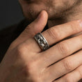 Load image into Gallery viewer, Oxidized sterling silver Michelangelo Moses spinner band worn on finger, portrait relief detail on rotating center, natural lifestyle hand shot with shallow depth of field.