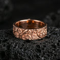 Load image into Gallery viewer, Rose gold plated sterling silver floral pattern band on volcanic stone, sculpted daisy relief with deep contrast and botanical engraving, minimal high-end close-up.