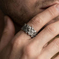 Load image into Gallery viewer, Oxidized sterling silver oni mask ring worn on finger, Japanese demon face relief detail, natural lifestyle hand shot with shallow depth of field.