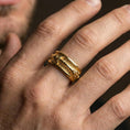 Load image into Gallery viewer, Gold plated arrow spinner band worn on finger, detailed arrow motif on rotating band with rugged texture, premium lifestyle jewelry photo.