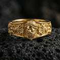 Load image into Gallery viewer, Gold plated Zeus portrait band ring on volcanic rock, detailed god face relief with ornate classical scrollwork, luxury jewelry product photography.