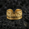 Load image into Gallery viewer, Gold plated Last Supper engraved band ring on volcanic rock, detailed apostle scene relief with architectural border accents, luxury jewelry product photography.