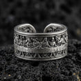 Load image into Gallery viewer, Oxidized sterling silver Last Supper engraved band ring on dark volcanic rock, high-relief apostle scene with detailed table setting, premium macro product shot.