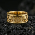 Load image into Gallery viewer, Gold plated lion medallion band ring on volcanic rock, detailed lion head relief panels with gothic cross centerpiece, luxury jewelry product photography.