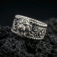 Load image into Gallery viewer, Oxidized sterling silver lion head signet ring on dark volcanic rock, bold roaring lion relief with ornate scrollwork shoulders and rope-edge borders, premium macro product shot.