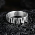 Load image into Gallery viewer, Oxidized sterling silver band ring on dark volcanic rock, bold faceted chevron cuts with deep shadowed grooves, clean macro product photography.
