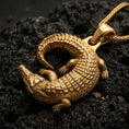 Load image into Gallery viewer, Gold plated crocodile pendant with detailed armored scales, curved animal body, and bold wildlife design showcased on black volcanic rock in a refined macro jewelry image