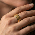 Load image into Gallery viewer, Gold plated square-grid pattern ring worn on finger, rich warm glow over the repeating geometric squares, lifestyle jewelry shot.