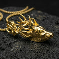 Load image into Gallery viewer, Gold plated stag pendant with realistic deer head, branching antler design, and bold woodland-inspired silhouette showcased on black volcanic rock in a refined macro jewelry image